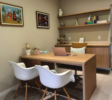 Sala de atendimento clara, com mesa de madeira e cadeiras